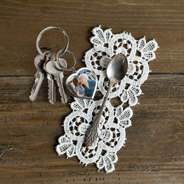 Heart-shaped photo keyring on lace doily with vintage spoon, grandmother and grandchild photo inside